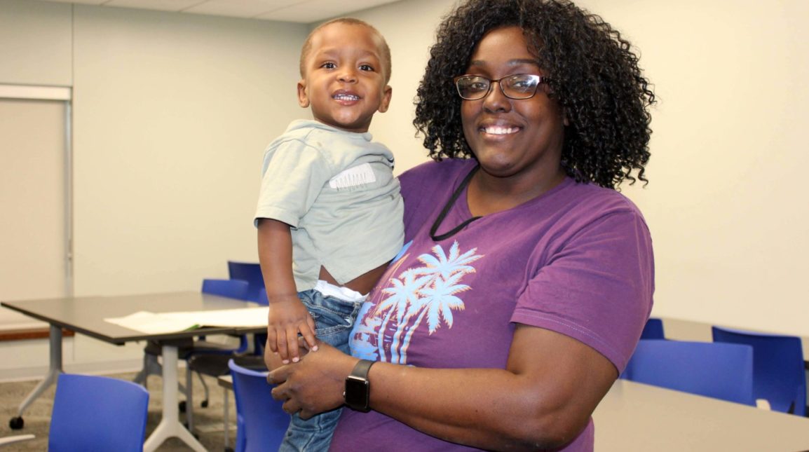 A parent from Porter-Leath smiles at the camera with her son.