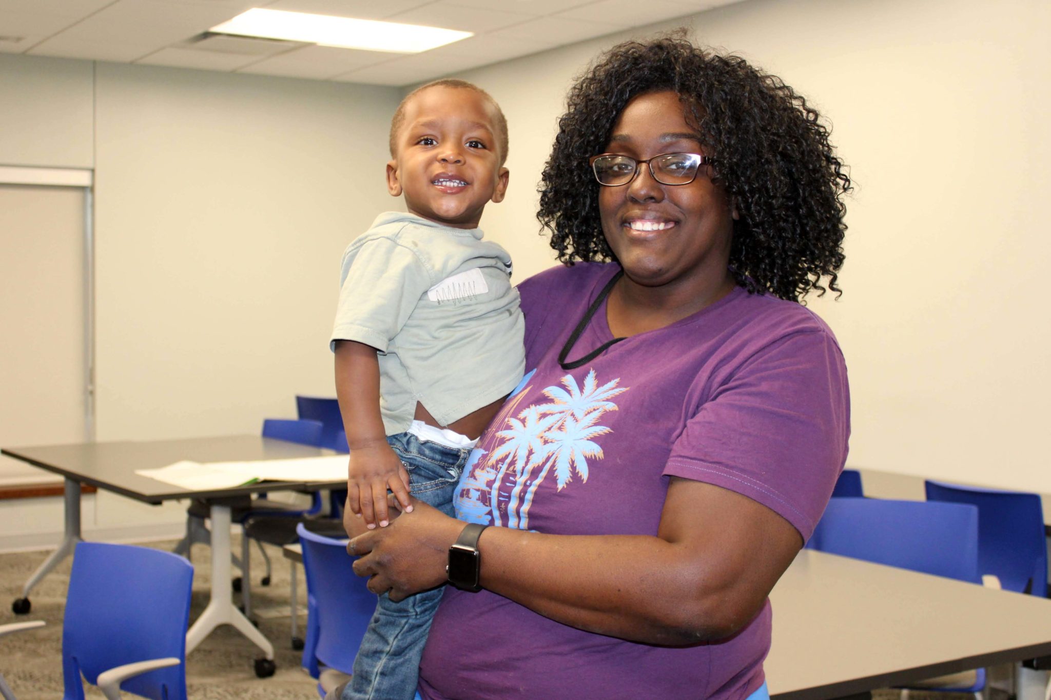 A parent from Porter-Leath smiles at the camera with her son.