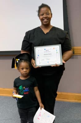 A family proudly displays their LENA Start graduation certificate.