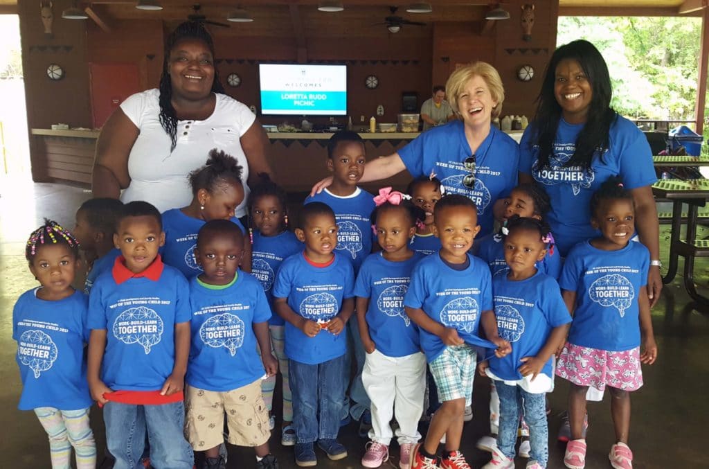 Loretta stands with a group of children.