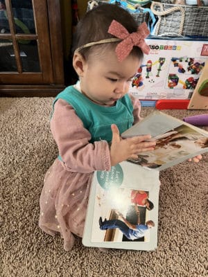 infant wearing a LENA device and reading books