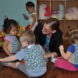 Early childhood educator sitting on the floor talking with a group of toddlers