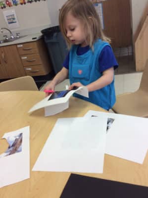 preschooler wearing a LENA device and cutting a piece of paper