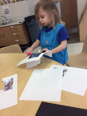 preschooler wearing a LENA device and cutting a piece of paper