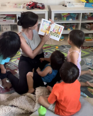 family child care providers reads with a group of children in her home