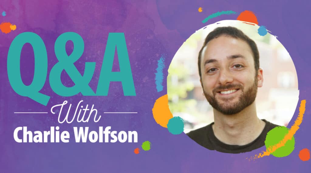 A graphic with the text "Q&A With Charlie Wolfson" on a purple background, next to a circular photo of a smiling man with a beard and short hair. Colorful paint splashes surround the photo.