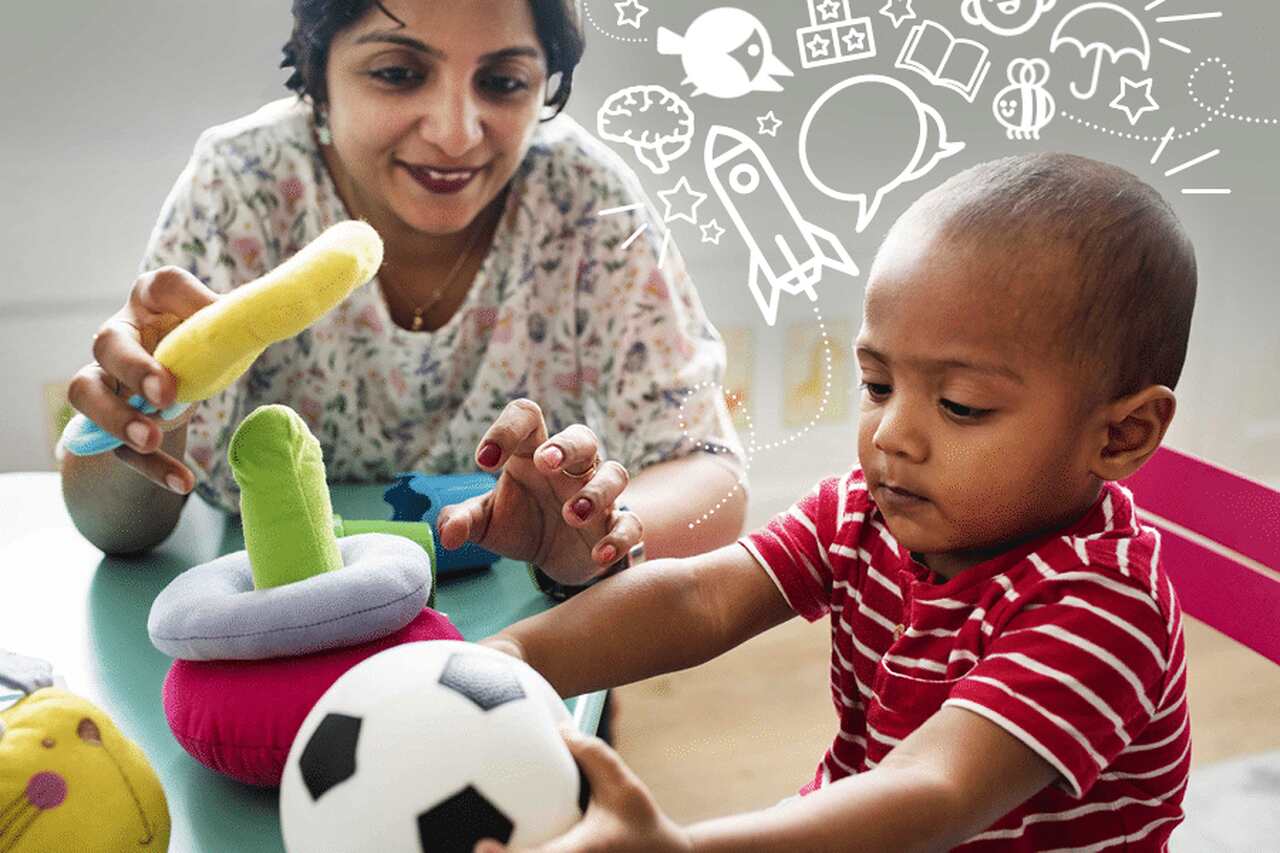 A woman and a toddler play with soft toys at a table. The child holds a soccer ball, while the woman helps with a stacking toy. White doodles of books, rockets, and speech bubbles decorate the background.