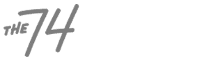 Gray logo with the text "THE 74" in a handwritten-style font on a transparent background.