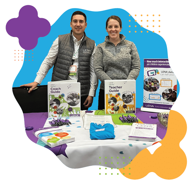 Two people stand behind a table with educational materials, including "Coach Guide" and "Teacher Guide" booklets, pens, brochures, and a blue t-shirt. Colorful abstract shapes decorate the image border.