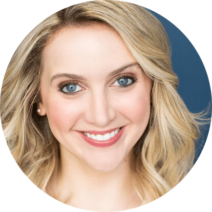A smiling woman with long blonde hair, blue eyes, and light skin, wearing natural makeup and pearl earrings, against a dark blue background.
