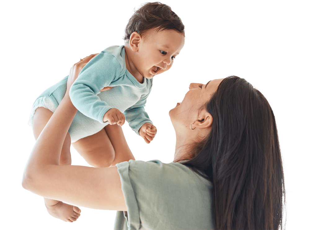 A woman smiles and lifts a laughing baby dressed in a light blue onesie. The baby looks down at her, and both appear happy and joyful against a plain white background.