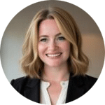 A woman with shoulder-length blonde hair, wearing a black blazer over a white blouse, is smiling in a professional indoor setting.