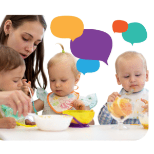 A woman helps three toddlers eat at a table. Colorful speech bubbles are illustrated above their heads, suggesting conversation or communication among them.