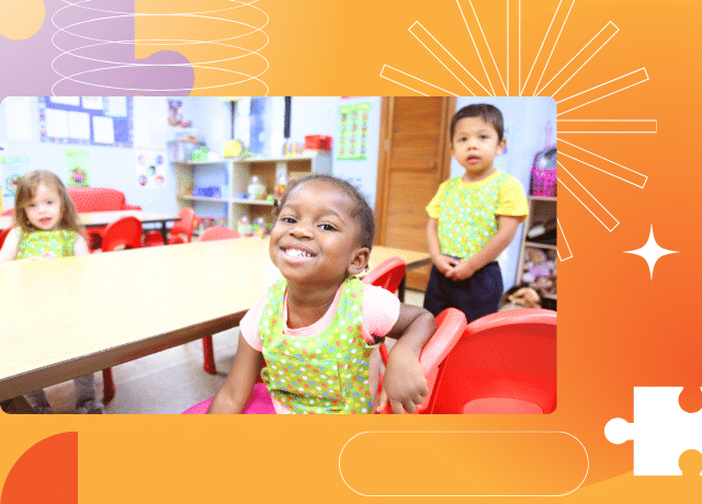 Three young children in a classroom sit and stand by a table, smiling and wearing green aprons. The background is orange with abstract shapes and puzzle piece designs.