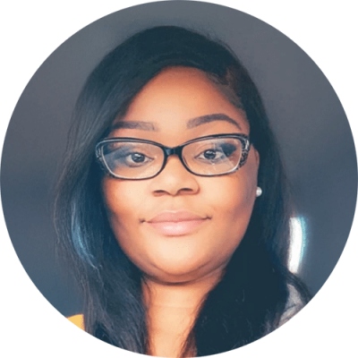 A woman with long dark hair, wearing glasses and a light pink lipstick, smiles softly at the camera. She is photographed against a plain, dark background in a circular frame.